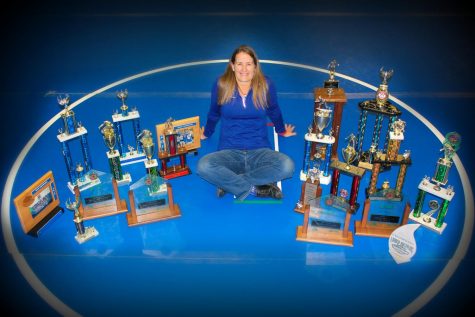 Celebrated girls wrestling coach Barb Morgan sits, surrounded by her trophies. Her newest prize celebrates her efforts as coach for the entire region. 