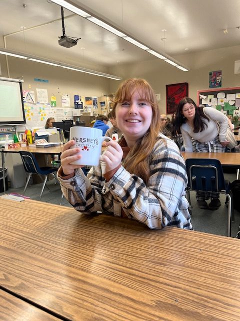 Madeline Dean smiling proudly for the camera with her favorite hot cocoa mug