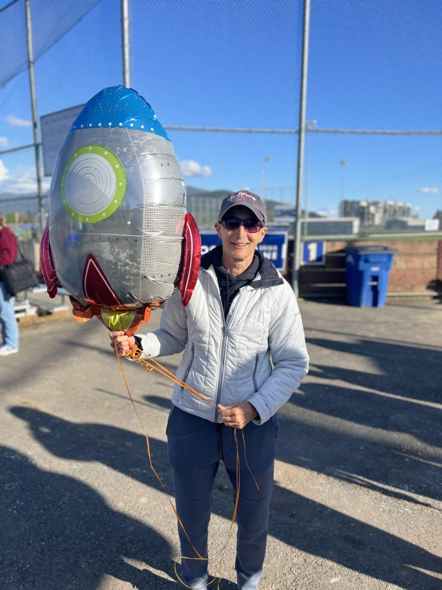 Stacy Price posing with a rocket balloon in honor of her son Logan Price